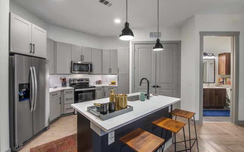 a kitchen with stainless steel appliances and wooden floors at The Ramble and Rose